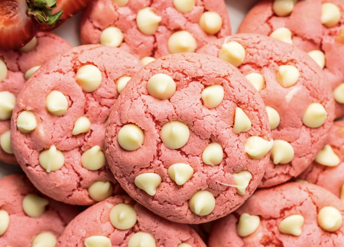 Pink cookies with white chocolate chips on a plate.